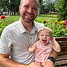 man, baby, child, smiling, outdoor, park, bench, flowers, nature, greenery, happy, family, portrait, casual_clothing, headband, sunlight, daytime, person, grass, tree
