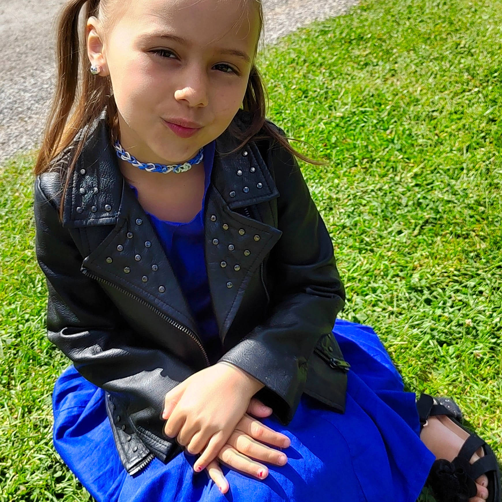 Inaya participe au concours pour gagner de l'argent avec cette photo : child, electric_blue, facial_expression, fashion_accessory, formal_wear, fun, grass, grassland, headwear, jewellery, pattern, people_in_nature, person, plaid, school_uniform, sitting, sleeve, uniform