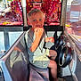 Lyam participe au concours pour gagner de l'argent avec cette photo : child, boy, amusement_ride, seat, steering_wheel, window, reflection, colorful, lights, sunlight, casual_clothing, shorts, tshirt, footwear, smile, happy, indoor, playful, hand, seatbelt