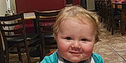 Giovanni joined the competition — help win amazing prizes! baby, child, high_chair, bib, smile, restaurant, waitress, table, chair, floor, tile_floor, wall, sign, light, red_bench, person, indoor, hair, cute, toddler