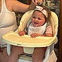 Clara joined the competition — help win amazing prizes! baby, child, high_chair, headband, bib, smile, happy, indoor, person, arm, furniture, china_cabinet, cup, teapot, tableware, pink_clothing, feeding_chair, infant, cute, family