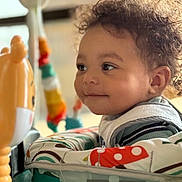 Ky Son is registered to the contest to win money with this photo: toddler, child, curly_hair, toy, lion_toy, play_area, baby_seat, infant, side_profile, indoor, colorful, smile, face, cute, young_child, curious, baby_clothes, soft_light, closeup, person