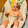 baby, infant, child, portrait, smiling, sitting, bouncer, baby_chair, peach_clothing, hat, bow, bib, leggings, socks, patterned_clothing, animal_print, giraffe, monkey, indoor, wood_paneling