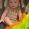 baby, child, car_seat, plush_toy, green, orange, toddler, clothing, rosy_cheeks, indoor, cute, person, smiling, winnie_the_pooh, soft_toy, seat, infant, face, head, comfort
