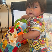 Darian is registered to the contest to win money with this photo: baby, carpet, child, colorful_clothing, curious, expression, face, footwear, furniture, hair, hand, home, indoor, person, play, room, sesame_street, standing, toddler, toy_walker