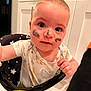 baby, child, face_paint, high_chair, kitchen, curious, infant, paint_smudge, onesie, cute, expression, indoor, person, seat, young_child, hand, cheeks, nose, clothing, closeup