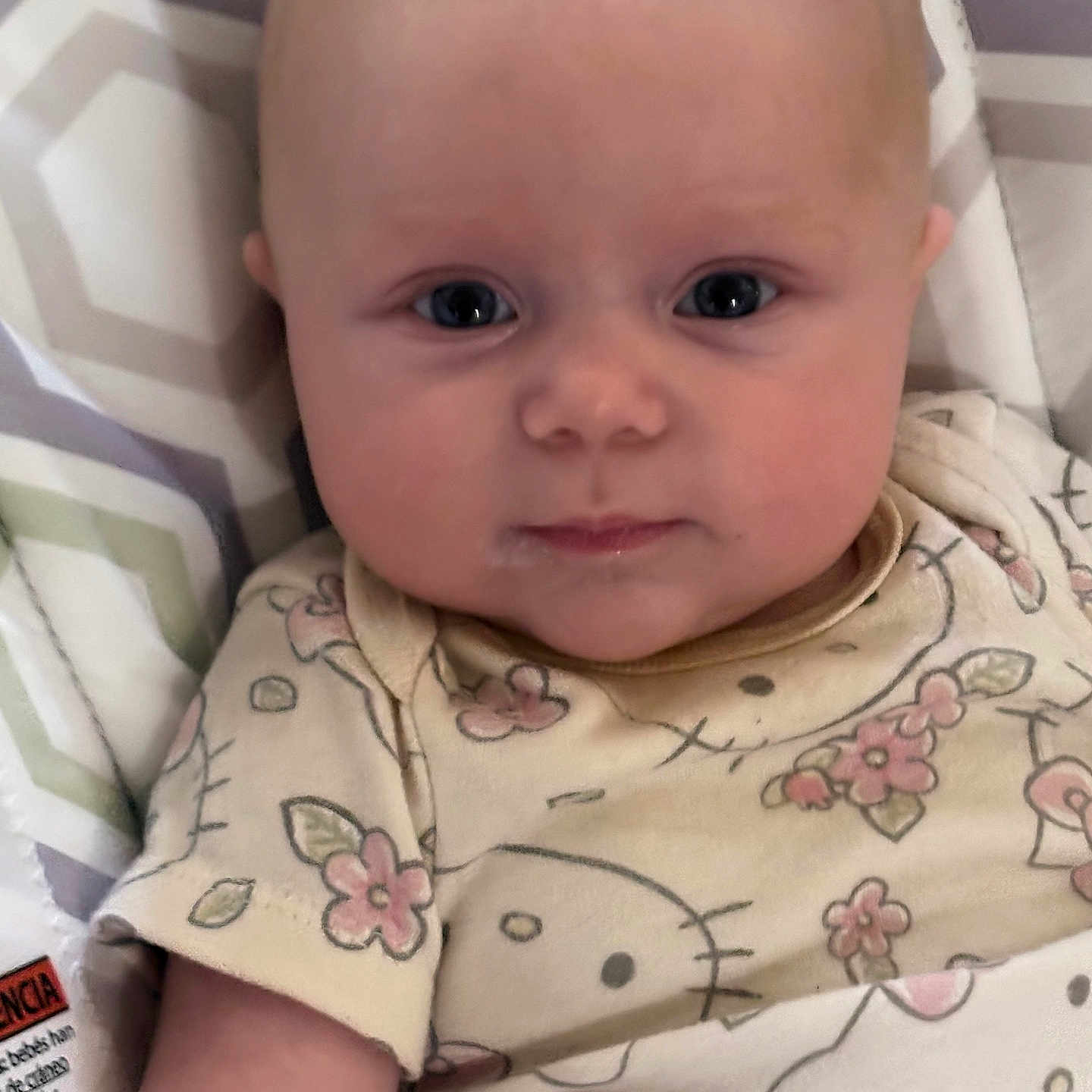 Scarlett is registered to the contest to win money with this photo: baby, blue_eyes, child, chubby_cheeks, close_up, clothing, cushion, cute, expression, face, floral, head, indoors, infant, lying_down, patterned_outfit, person, portrait, skin, soft_lighting