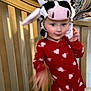 child, baby, onesie, red_clothing, heart_pattern, cow_hat, crib, blanket, bedroom, indoor, person, motion_blur, cute, playful, headwear, infant, toddler, furniture, soft_toys, sleepwear