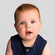 Frankie is registered to the contest to win money with this photo: baby, child, face, portrait, blue_eyes, curious, expression, infant, sleeveless_top, navy_blue, soft_skin, close_up, light_background, studio_photo, cute, young, person, head_and_shoulders, innocent, adorable