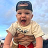 Bentlee Barron is registered to the contest to win money with this photo: baby, child, person, cap, hat, shirt, hands, tattoo, outdoor, sky, clouds, red_shorts, smiling, happy, cute, infant, portrait, fun, playful, expression