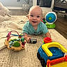 Bentlee Barron is registered to the contest to win money with this photo: baby, toys, rug, smile, indoor, plant, fireplace, dog, wood_floor, child, happy, colorful, playful, person, living_room, furniture, blanket, cute, floor, toddler