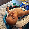 baby, infant, child, portrait, indoor, playroom, activity_walker, baby_toy, colorful_toys, toy_bin, beads, play_table, rug, carpet, sitting, lying_down, looking_at_camera, face, bare_arms, home