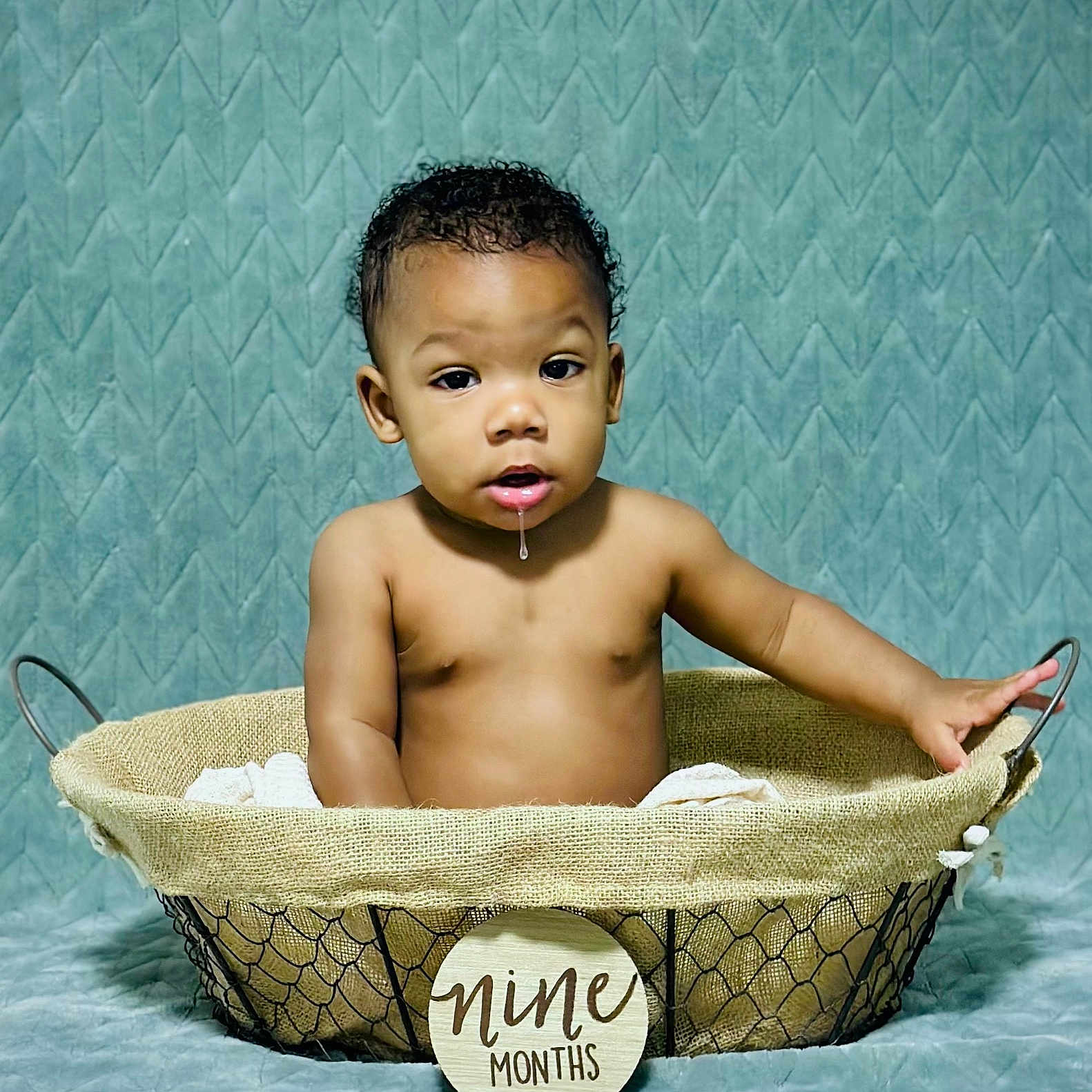 Sakani Lay is registered to the contest to win money with this photo: baby, background, basket, child, curly_hair, cute, drool, expression, fabric, hand, indoors, infant, milestone, milestone_sign, nine_months, photo_shoot, portrait, sitting, skin, texture