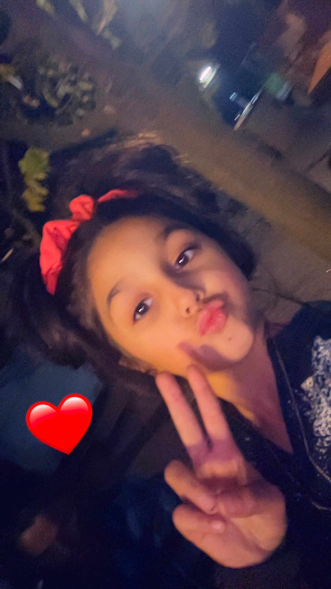 Shainna participe au concours pour gagner de l'argent avec cette photo : child, girl, peace_sign, red_bow, hair_accessory, face, portrait, selfie, hand_gesture, expression, emoji, heart_emoji, dark_background, casual_clothing, indoor, young_person, fun, playful, person, gesture