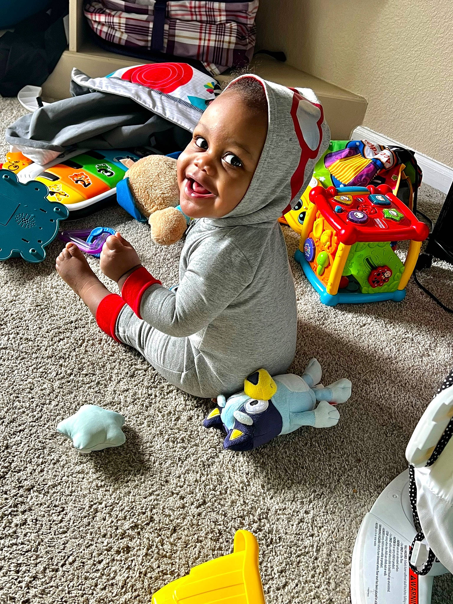 Junior is registered to the contest to win money with this photo: baby, baby_products, baby_toddler_clothing, baby_toys, child, event, flooring, fun, happy, holiday, person, plastic, play, room, sitting, smile, soil, stuffed_toy, toddler, toy