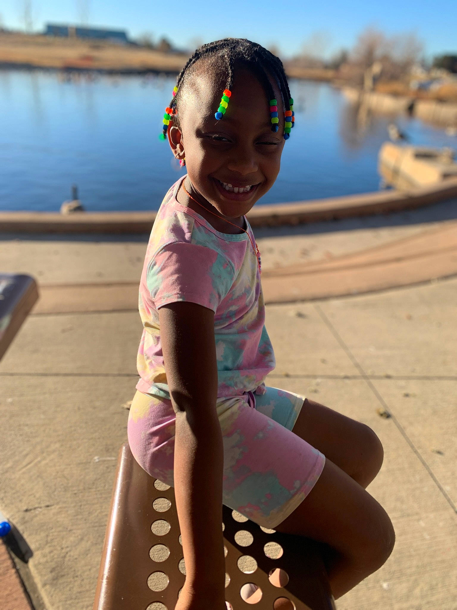 Emery is registered to the contest to win money with this photo: barefoot, boats_and_boating_equipment_and_supplies, body_of_water, child, fun, happy, human_leg, joy, lake, leisure, person, personal_protective_equipment, recreation, sitting, sky, smile, thigh, toddler, travel, vacation
