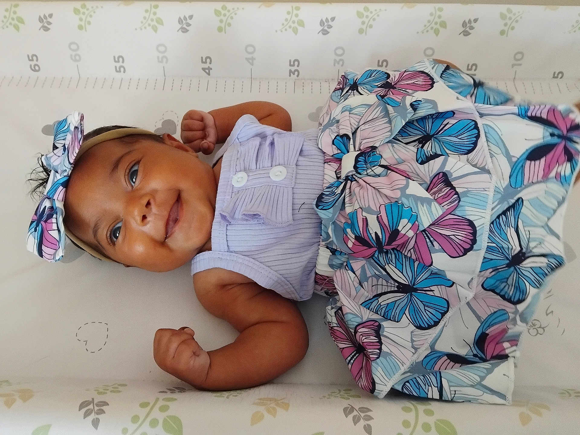 Willow joined the competition — help win amazing prizes! baby, smiling, infant, headband, butterfly_pattern, skirt, clothing, lying_down, baby_mat, measurement_marks, fists, cute, happy, child, portrait, indoor, skin, face, person, newborn