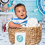 baby, basket, blanket, blue, child, clock, curly_hair, cute, decor, face, indoor, infant, nautical_theme, portrait, sitting, soft_texture, star_pattern, striped_clothing, white, wooden_background