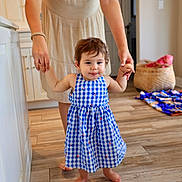 Raea joined the competition — help win amazing prizes! toddler, child, person, dress, blue_checkered, indoor, kitchen, floor, wooden_floor, barefoot, adult_hands, helping, walking, basket, blanket, home, family, smiling, young_child, support