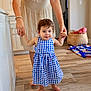 toddler, child, person, dress, blue_checkered, indoor, kitchen, floor, wooden_floor, barefoot, adult_hands, helping, walking, basket, blanket, home, family, smiling, young_child, support