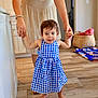 toddler, child, dress, indoor, walking, person, hand_holding, floor, wooden_floor, home, basket, clothing, barefoot, adult, support, face, hair, room, door, furniture
