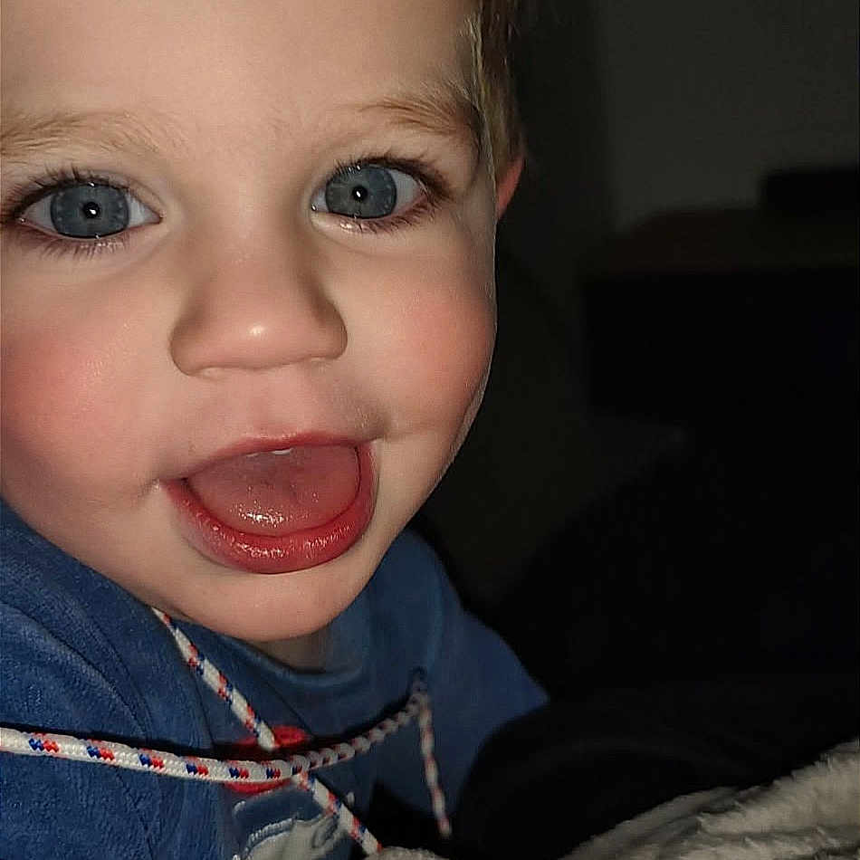 Mylan a rejoint le concours — aidez-le/la à gagner de superbes lots ! baby, blanket, blue_eyes, child, close_up, clothing, cozy, eyelashes, face, flash_photography, hand, indoor, mouth, nose, pajamas, portrait, rosy_cheeks, smiling, toddler, tongue_out