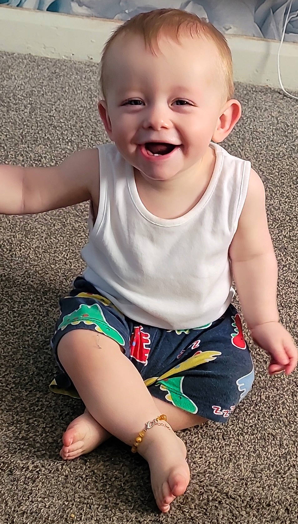 baby, barefoot, bracelet, carpet, casual_clothing, child, colorful_shorts, cute, dinosaur_print, fun, happy, indoor, person, playful, portrait, sitting, smile, toddler, white_shirt, young_child