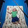 Aries is registered to the contest to win money with this photo: baby, infant, child, lying_down, portrait, face, curious, green_shirt, blue_shorts, blanket, pool_table, billiards, cue_stick, indoor, overhead_view, colorful, toy, patterned_blanket, relaxed, safe