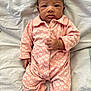 baby, infant, onesie, pink, floral_pattern, blanket, lying_down, hand, face, expression, cute, child, newborn, soft_texture, indoor, portrait, sleepwear, young, person, skin