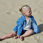 Méloa a rejoint le concours — aidez-le/la à gagner de superbes lots ! child, blonde_hair, pony_tail, denim_jacket, white_top, sand, barefoot, sitting, outdoor, sunlight, shadow, casual_clothing, young_child, curious_expression, legs, hand, summer, playful, nature, daytime