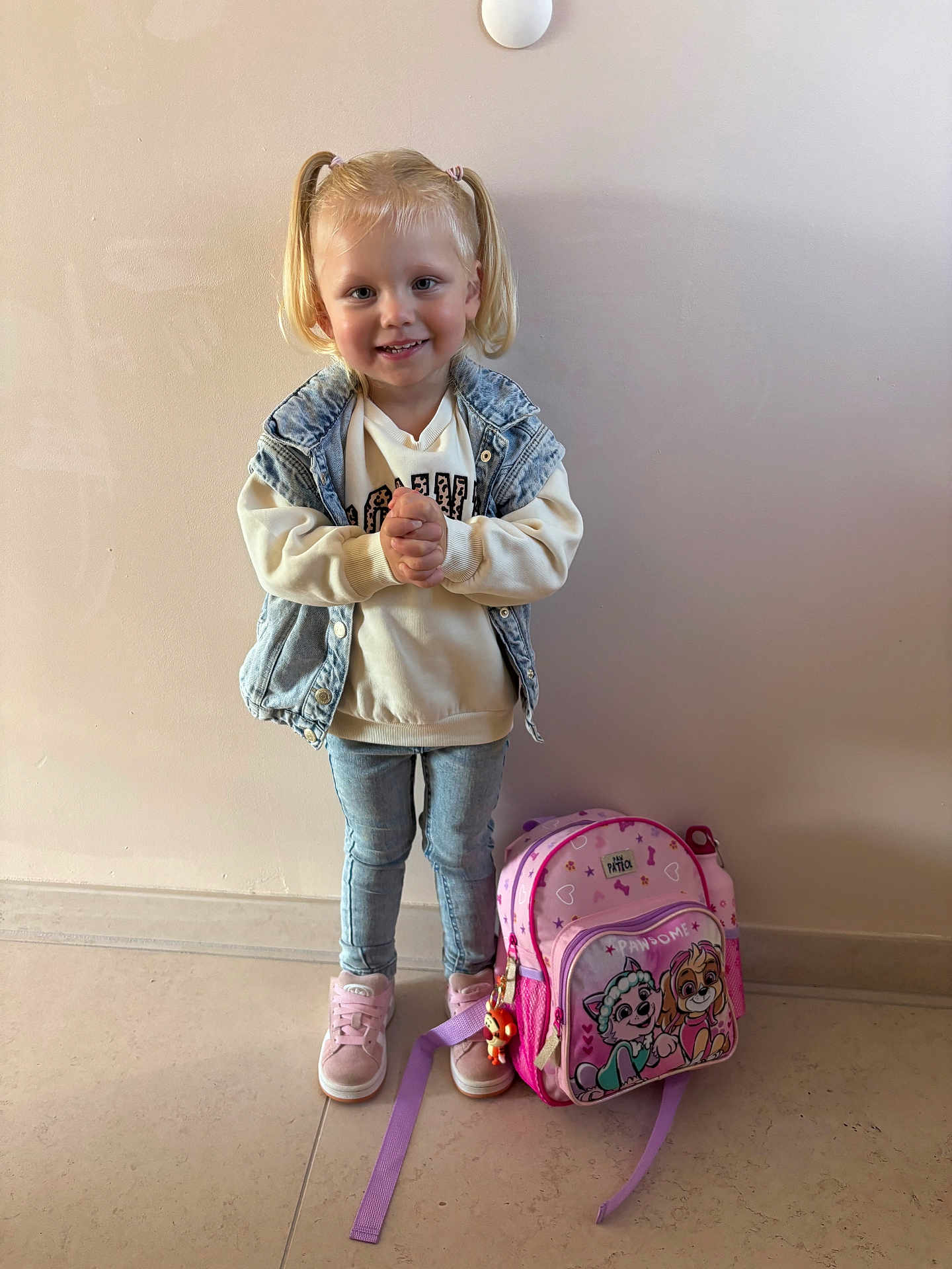Méloa participe au concours pour gagner de l'argent avec cette photo : child, girl, smile, standing, pigtails, denim_vest, sweatshirt, jeans, pink_shoes, backpack, cartoon_characters, indoor, floor, wall, happy, person, casual_clothing, toy, accessory, playful