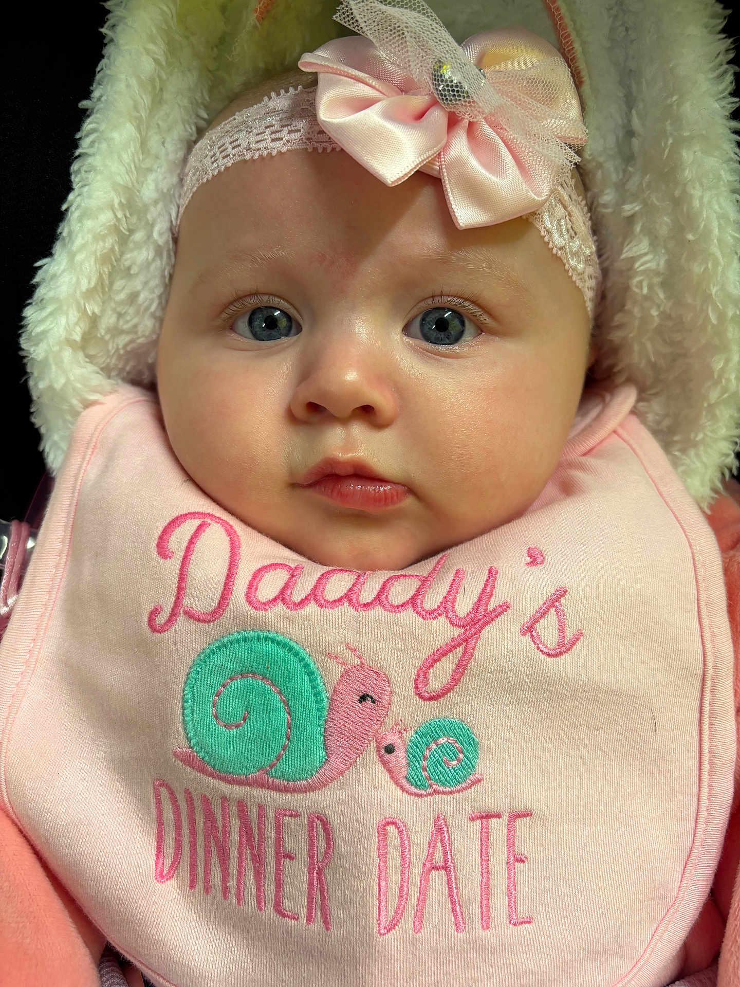 Silvia is registered to the contest to win money with this photo: baby, infant, face, headband, bow, blue_eyes, pink, bib, snail, clothing, cute, closeup, portrait, child, soft, fluffy, warm, expression, newborn, adorable