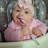 Silvia is registered to the contest to win money with this photo: baby, child, candy_cane, pink_clothing, headband, bow, high_chair, star_pattern, indoor, cute, chubby_cheeks, hand, face, blue_eyes, infant, pacifier, holiday, sweet, portrait, young_child