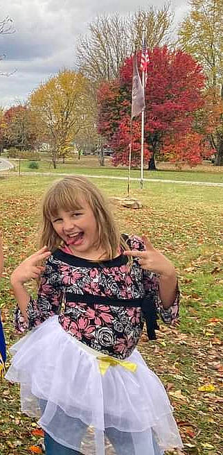 Cheyenne is registered to the contest to win money with this photo: botany, brown_hair, day_dress, event, flag, formal_wear, fun, grass, happy, joy, leaf, leisure, magenta, pattern, people_in_nature, person, plant, recreation, sky, smile