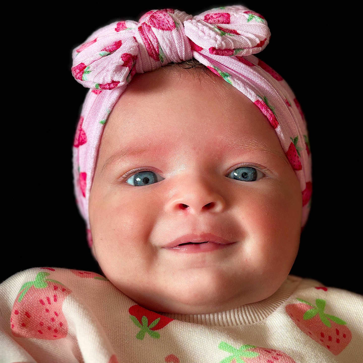 Orla joined the competition — help win amazing prizes! apparel, baby, baby_girl, black_background, blue_eyes, bow, child, closeup, clothing, cute, face, fashion, happy, headband, headwear, infant, pink, portrait, smile, strawberry_pattern