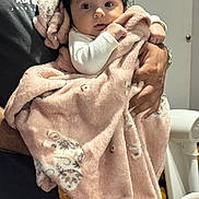 Zara joined the competition — help win amazing prizes! baby, child, blanket, pink_blanket, animal_print, infant, person, holding, hands, curious, wide_eyes, indoor, soft_texture, warm, clothing, adult, portrait, cute, newborn, family