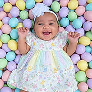 Amelia joined the competition — help win amazing prizes! baby, infant, smiling, happy, flower_headband, pastel_colors, easter_eggs, colorful, dress, patterned_clothing, cute, child, playful, lying_down, celebration, spring, holiday, portrait, hands_up, background