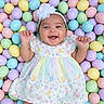 baby, infant, smiling, happy, flower_headband, pastel_colors, easter_eggs, colorful, dress, patterned_clothing, cute, child, playful, lying_down, celebration, spring, holiday, portrait, hands_up, background