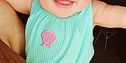 Victoria is registered to the contest to win money with this photo: baby, child, smiling, tongue_out, hat, pastel_colors, turquoise_outfit, shell_patch, arm, hand, adult, holding, portrait, indoor, happy, cute, face, infant, closeup, skin