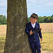 Ryder-gene is registered to the contest to win money with this photo: child, boy, toy_gun, tree, outdoor, field, grass, blue_suit, smile, happy, playful, portrait, nature, daylight, casual, shoes, young, person, standing, holding