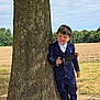 child, boy, toy_gun, tree, outdoor, field, grass, blue_suit, smile, happy, playful, portrait, nature, daylight, casual, shoes, young, person, standing, holding