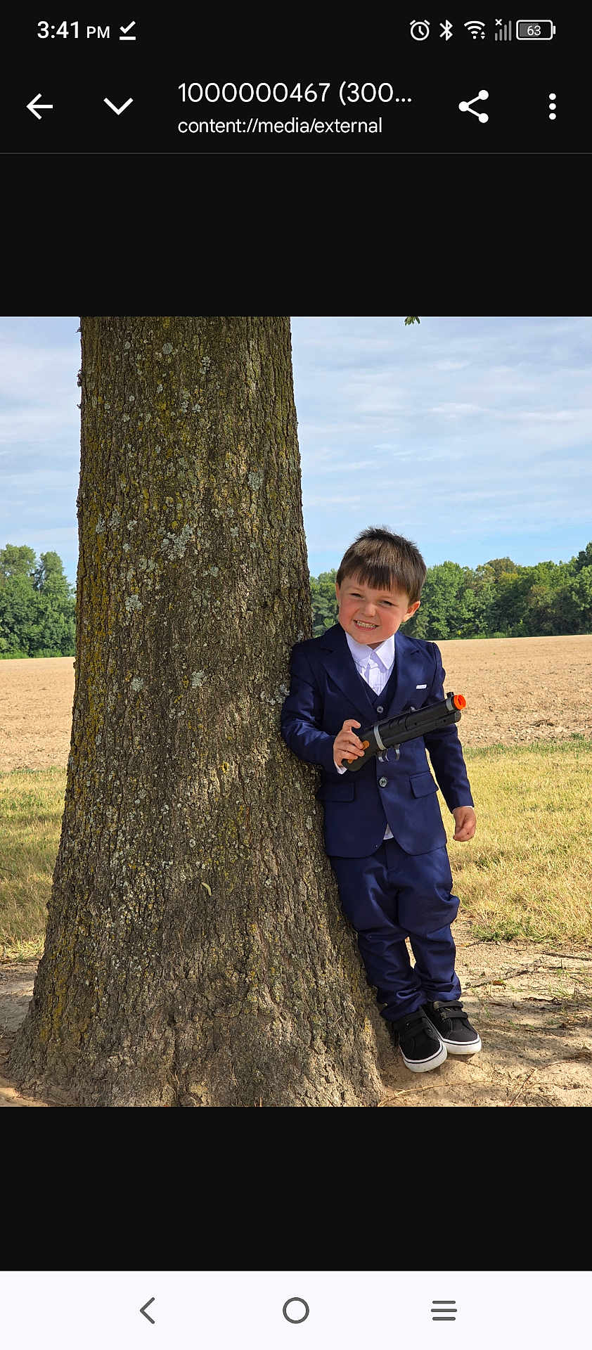 Ryder-gene is registered to the contest to win money with this photo: child, boy, toy_gun, tree, outdoor, field, grass, blue_suit, smile, happy, playful, portrait, nature, daylight, casual, shoes, young, person, standing, holding