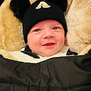 Adam a rejoint le concours — aidez-le/la à gagner de superbes lots ! baby, infant, smile, face, hat, beanie, pom_poms, blanket, clothing, warm, cozy, cute, child, portrait, indoor, happy, person, headwear, fuzzy, soft