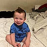 Hector is registered to the contest to win money with this photo: child, toddler, boy, smiling, sitting, bedroom, bed, blanket, pajamas, blue_clothing, portrait, indoors, happy, face, brown_hair, bare_feet, baby, bed linens, home, candid