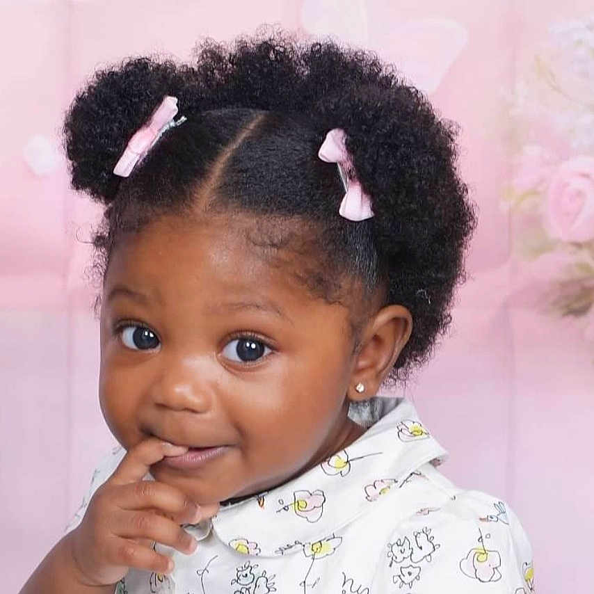 Chaya is registered to the contest to win money with this photo: toddler, child, girl, portrait, curly_hair, pink_bows, cute, smiling, finger_on_mouth, floral_background, white_shirt, indoor, closeup, adorable, young_child, african_american, happy, funny_expression, baby, person