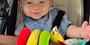 Jaxson joined the competition — help win amazing prizes! baby, stroller, smiling, child, plush_toy, toy, blue_clothing, head, face, seat, sitting, hand, foot, fabric, comfort, infant, casual_clothing, happy, indoor, baby_bib