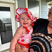 Avery is registered to the contest to win money with this photo: baby, child, smiling, sunhat, swimsuit, adult, holding, porch, door, window, clothing, happy, person, outdoor, skin, face, arm, pattern, flower, strawberry