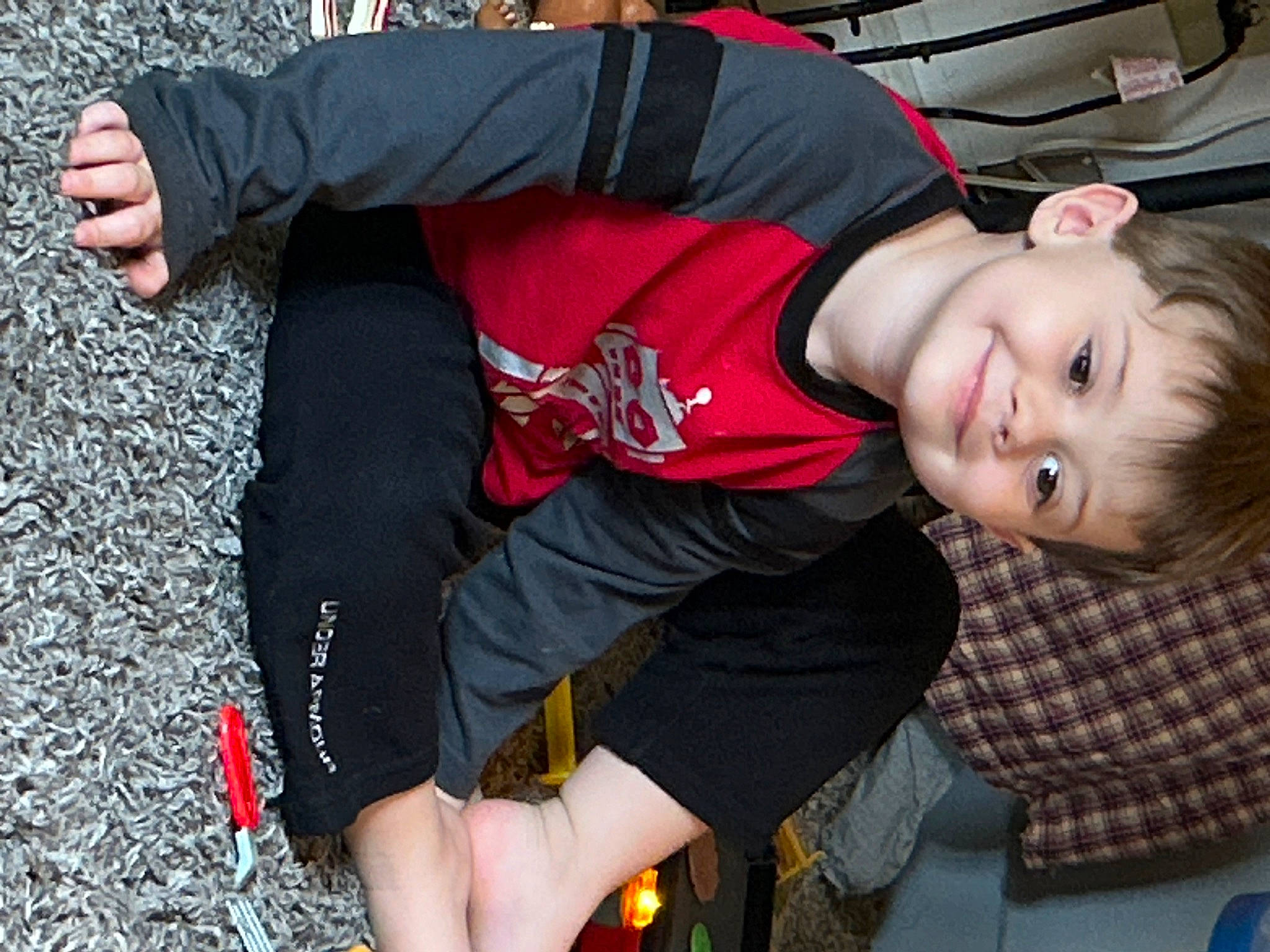 Brantley is registered to the contest to win money with this photo: asphalt, child, elbow, event, flash_photography, fun, grass, human_leg, joy, knee, leisure, person, shorts, sitting, smile, sportswear, t_shirt, thigh, toddler