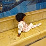 bench, casual_clothing, child, cityscape, curly_hair, floor, glass, indoor, jacket, marble, person, portrait, reflection, relaxed, seated, side_view, sneakers, urban, wall, young