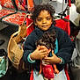 bag, casual, child, clothing, curly_hair, doll, floor, hand, holding, indoor, person, playful, portrait, public_transport, red, seat, sitting, stroller, toy, young